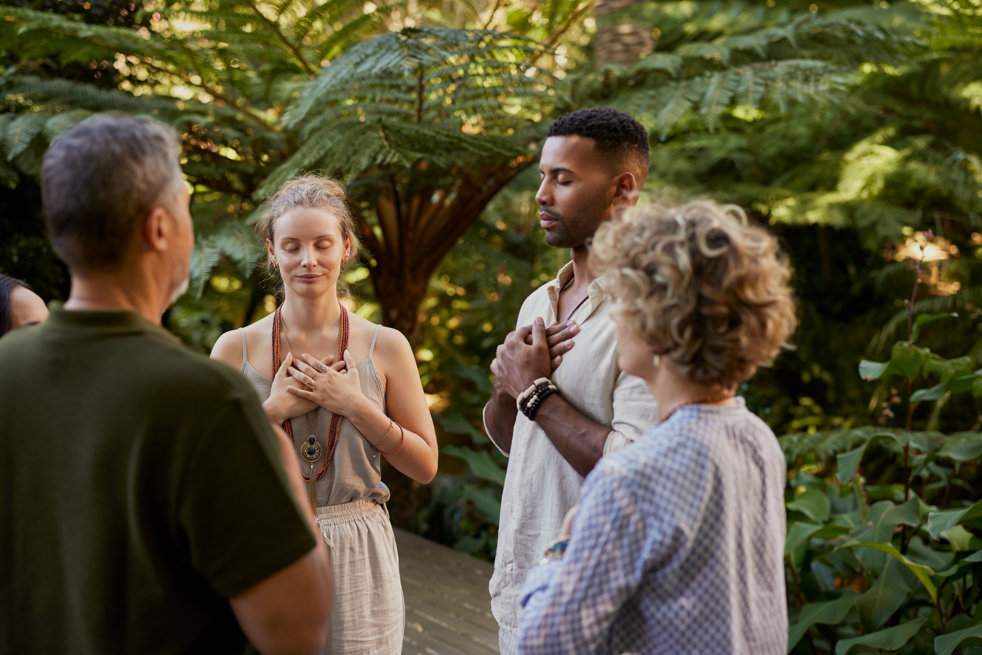 People meditating at holistic retreat with hands on heart